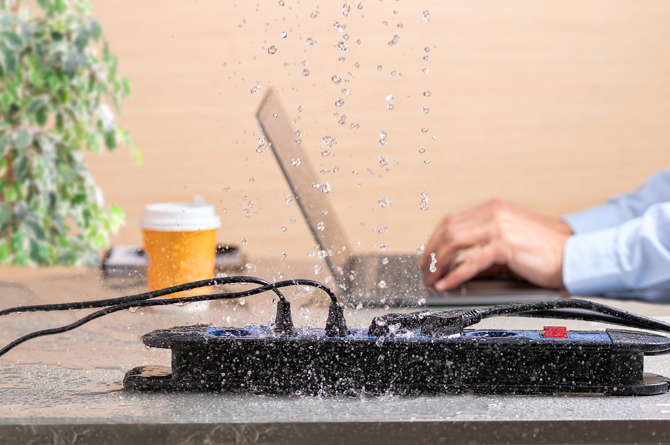 Close Up Of A Bank Of Plugs On A Desk With Water Leaks Falling Next To A Man Working In Danger Of Electrocution At Home Or Office